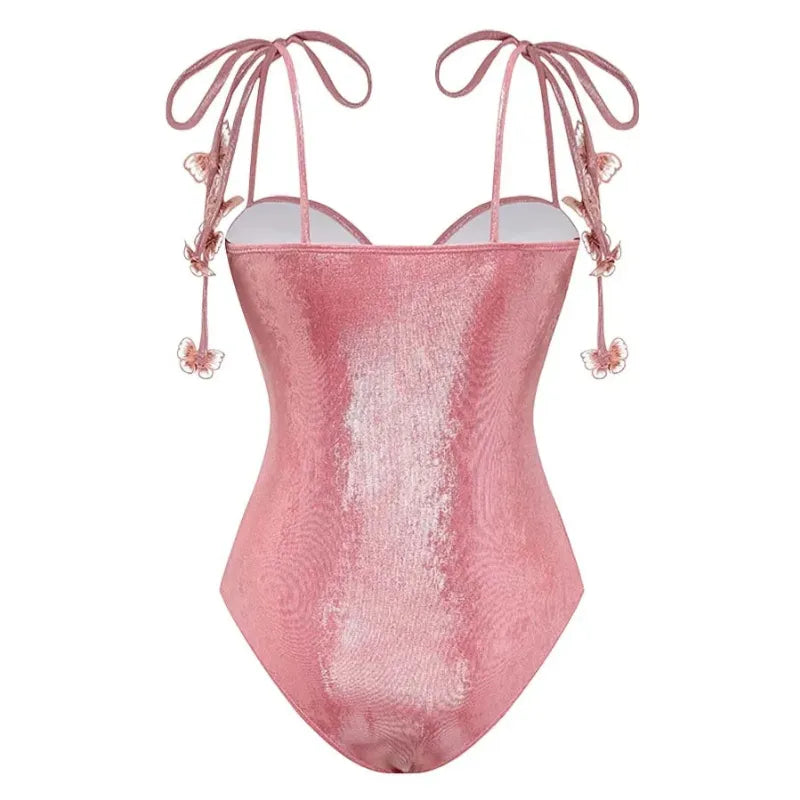 Maiô rosa cintilante com alças de amarrar nos ombros e apliques de borboletas em relevo por toda a peça, modelagem com bojo estruturado e brilho elegante.